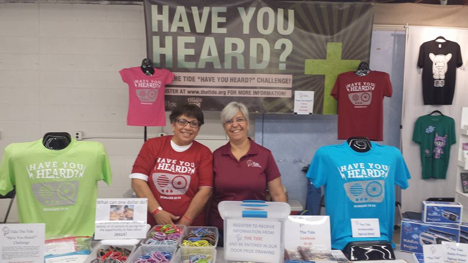Two women behind an event table smiling